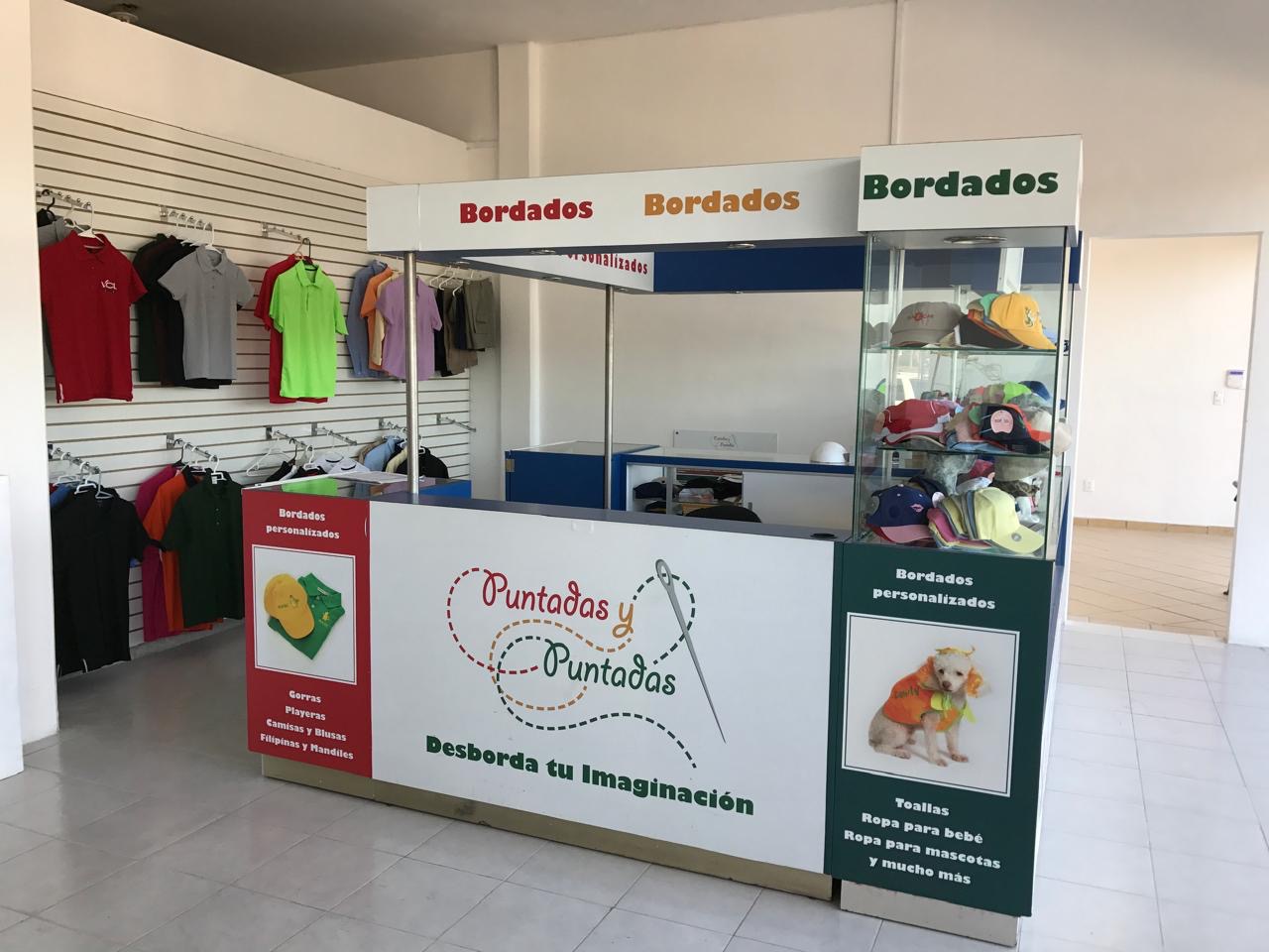 Isla de Bordado para Plazas Comerciales de 2.5X2.5 Mts, 4 Vitrinas y una Maquina Bordadora Industrial de 12 Colores. Rotulación Personalizada